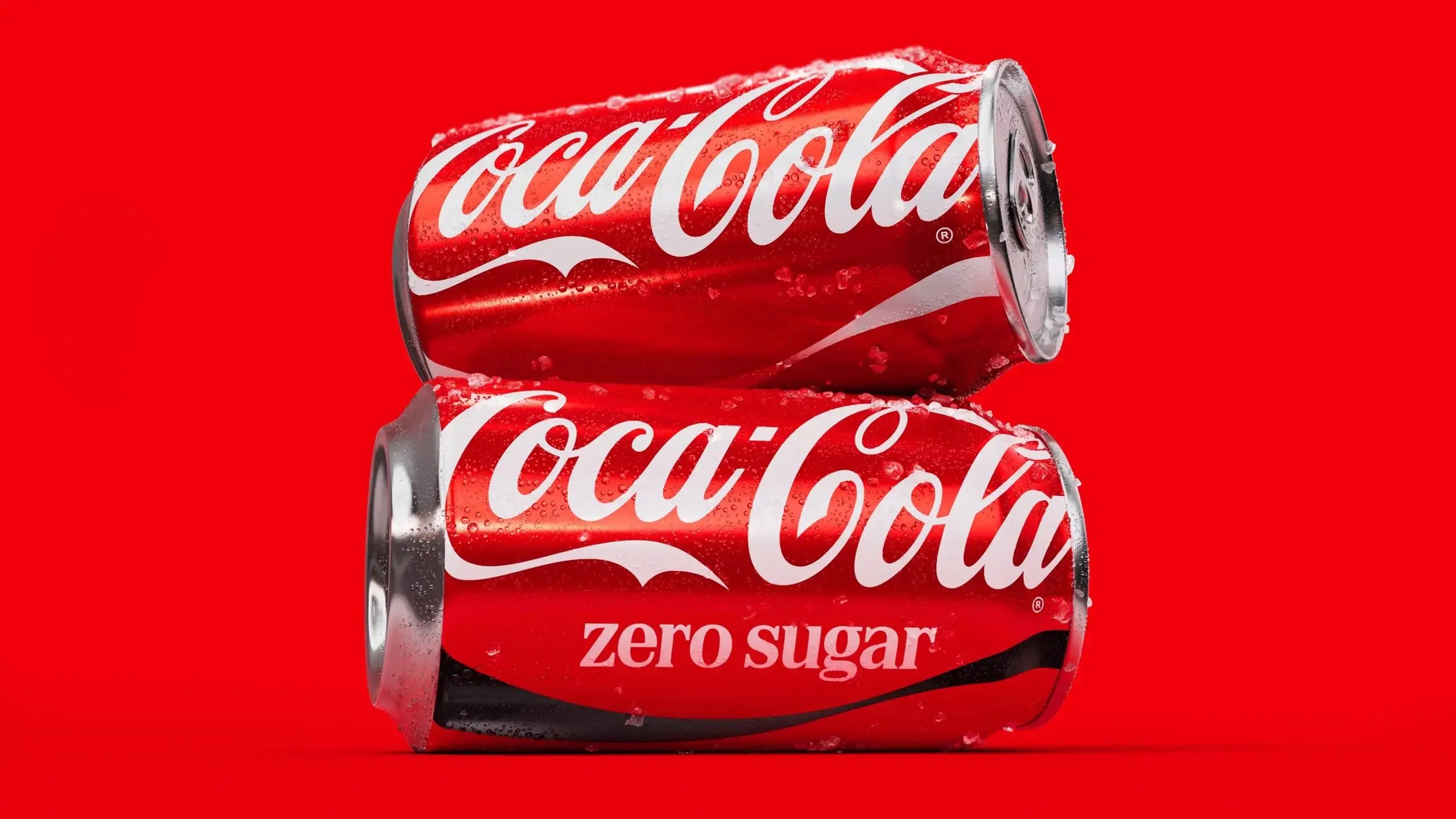 Une canette de Coca-Cola classique posée sur une canette Coca-Cola Zero Sugar, sur fond rouge.